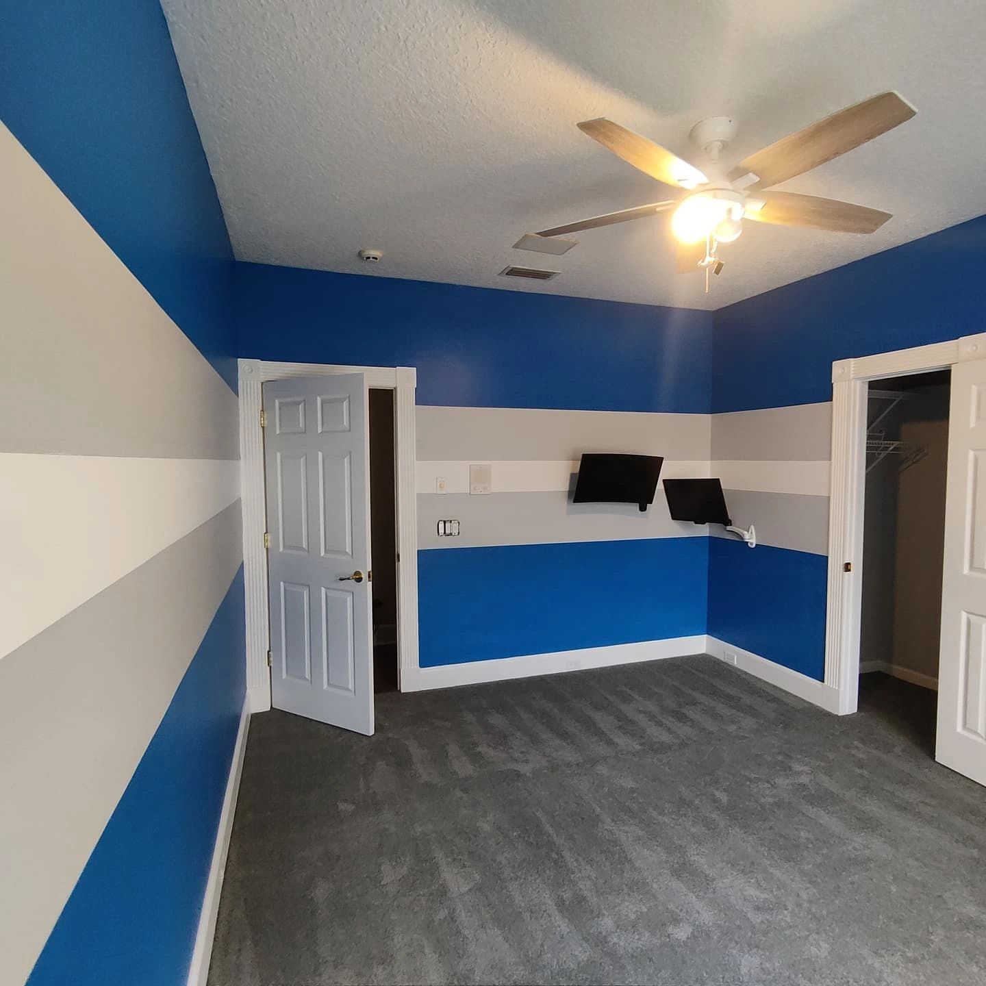 A bedroom with blue and white stripes and a ceiling fan