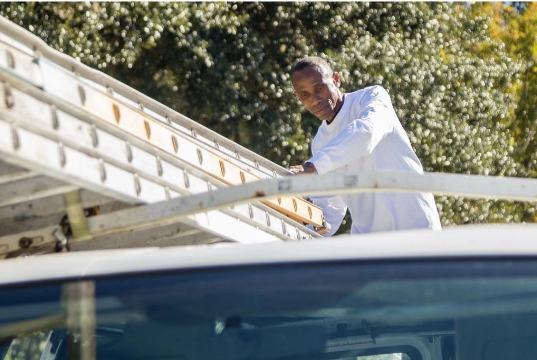 A man is climbing a ladder on top of a truck.