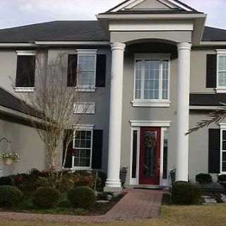 A large house with a red door and columns in front of it.