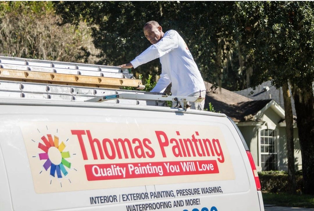 A man is working on the roof of a thomas painting van