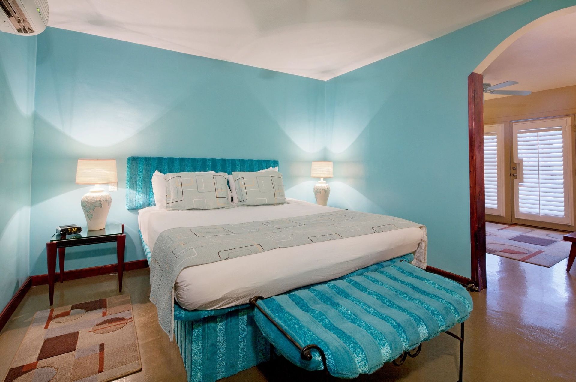 A bedroom with blue walls and a bed with white sheets