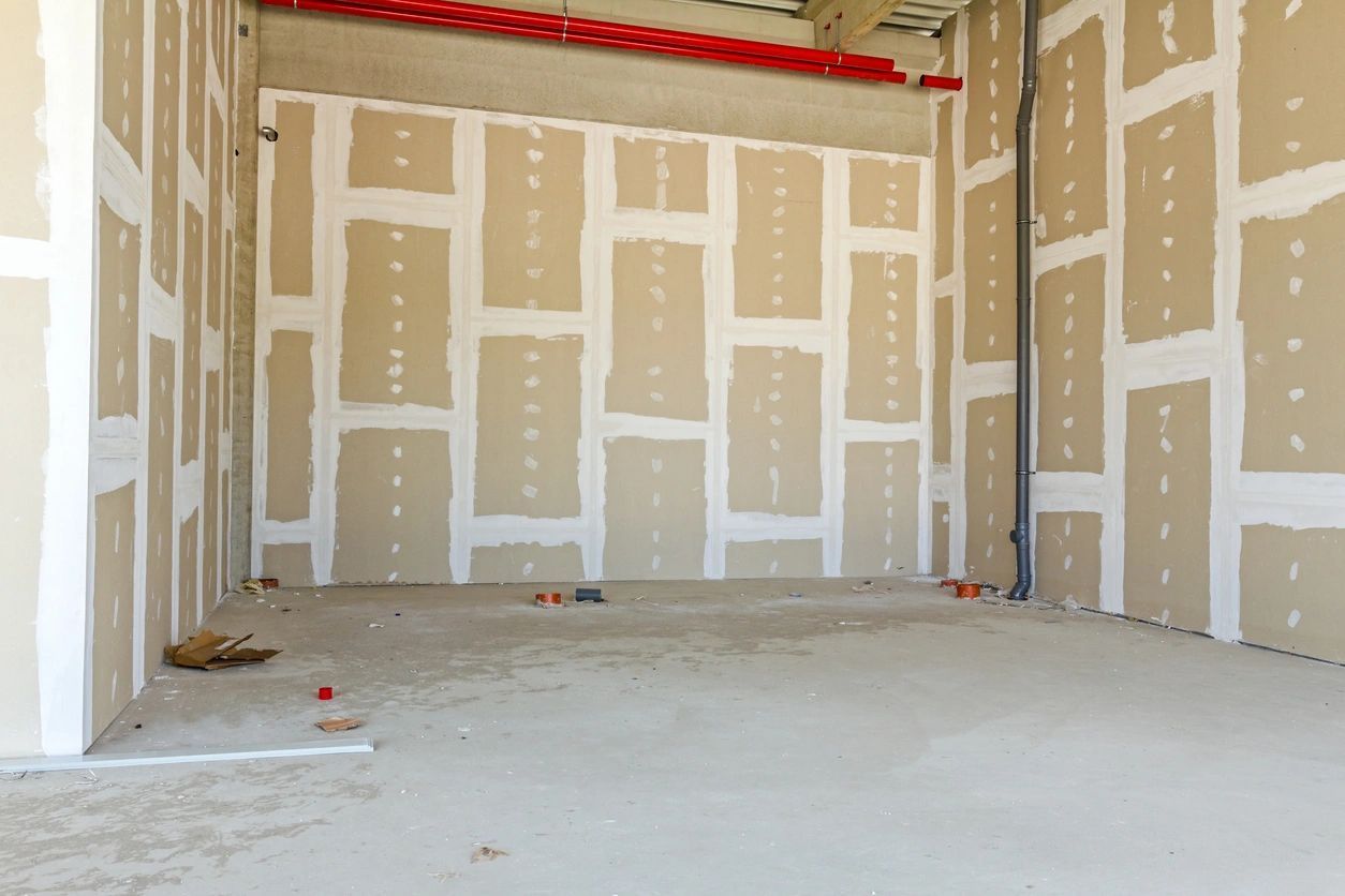 An empty room with drywall walls and a concrete floor.