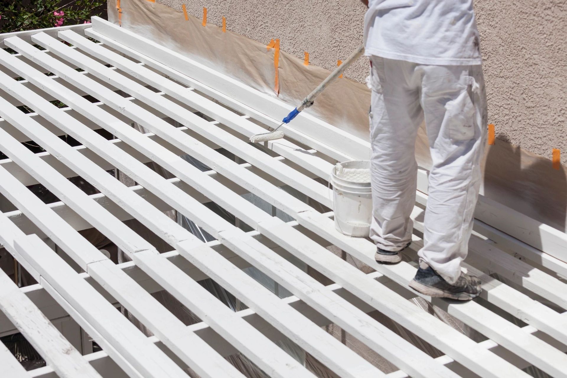 A man is painting a roof with a roller.