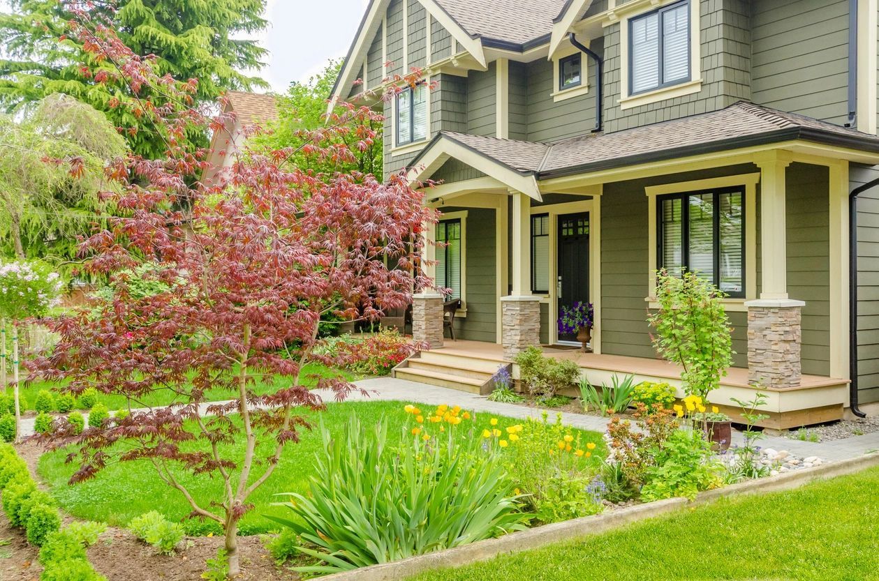 A large house with a lush green lawn and flowers in front of it.