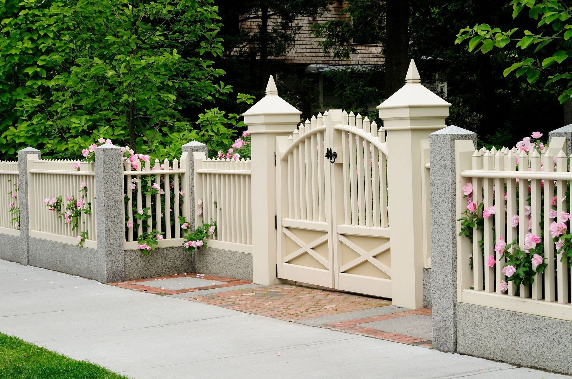 A white picket fence with a gate surrounded by flowers