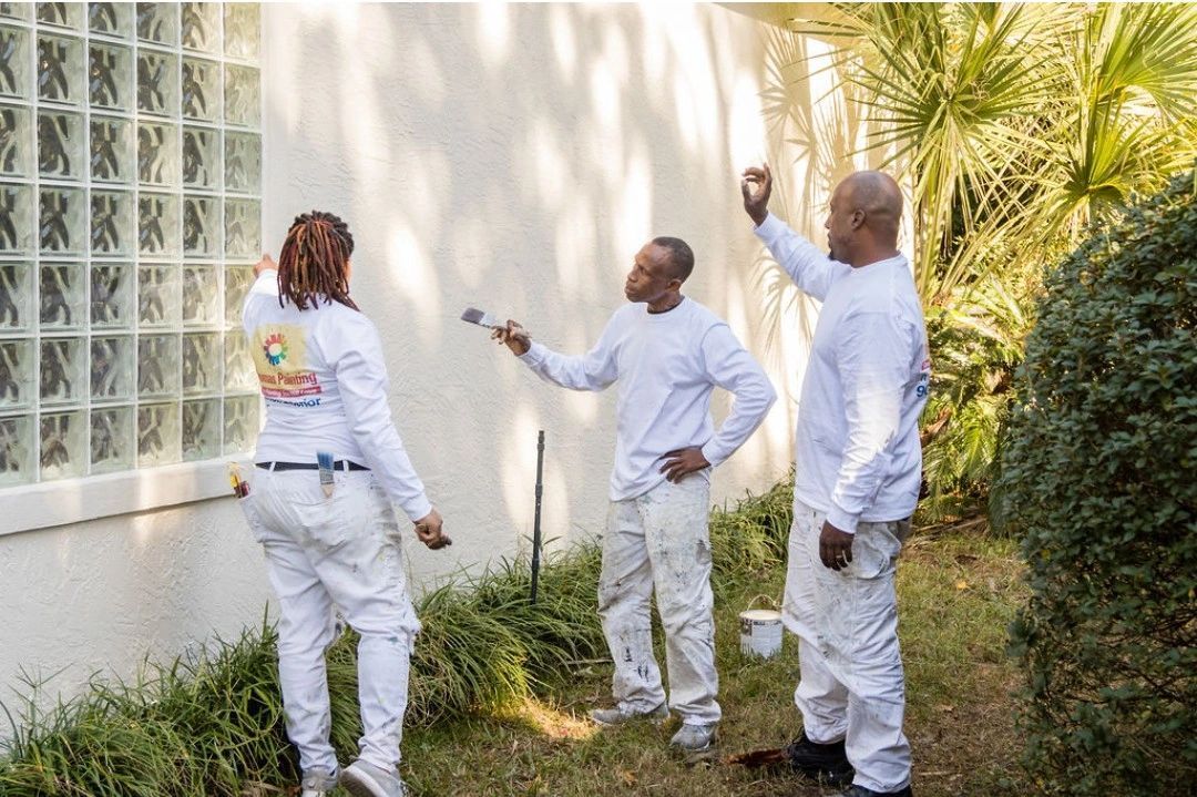 A group of people are painting a white wall.