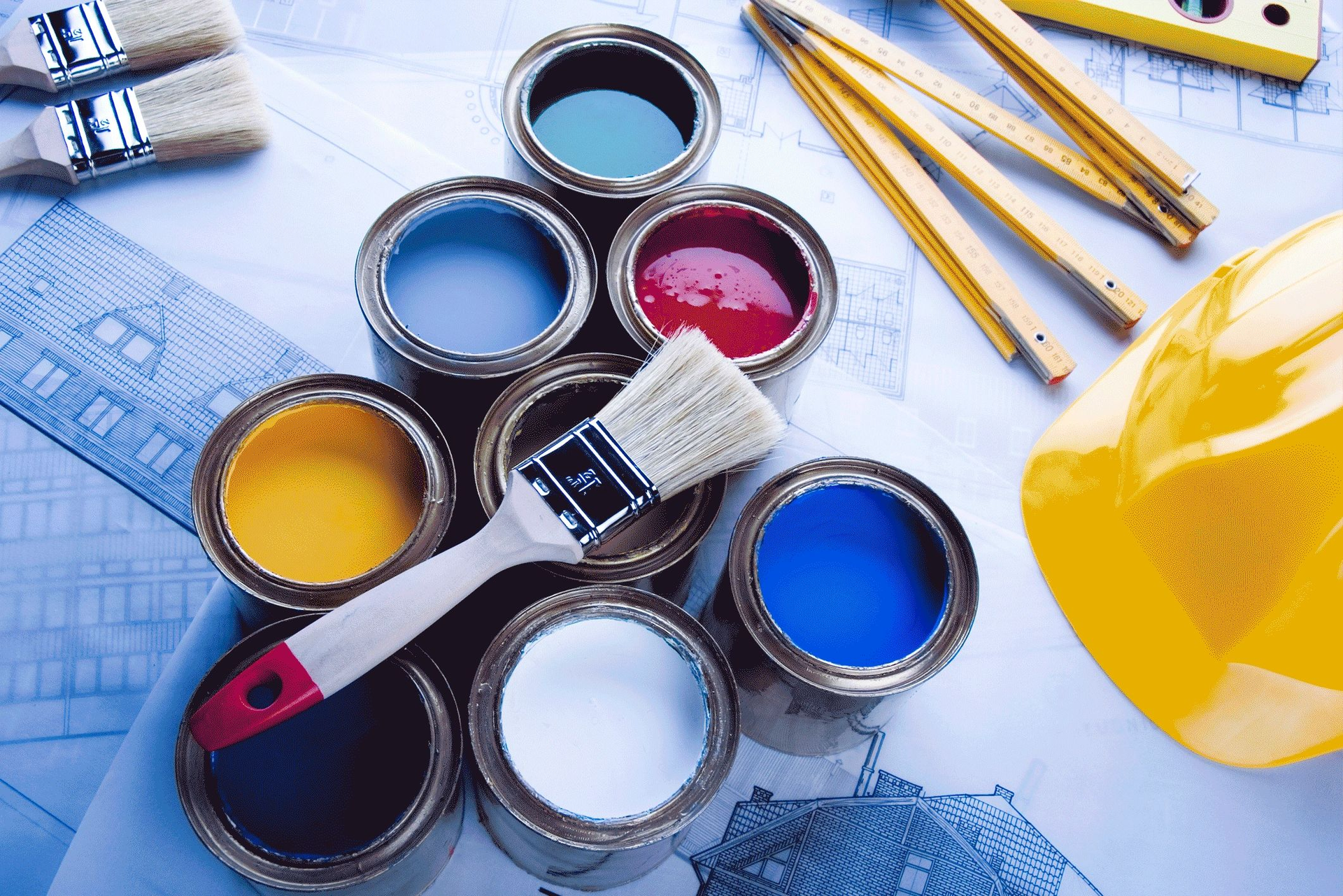 A yellow hard hat sits next to paint cans and brushes