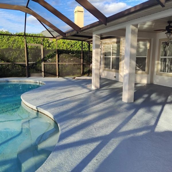 A large swimming pool is surrounded by a screened in area
