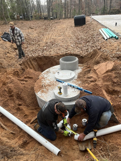 A septic tank being lowered into a hole by a crane; outdoor construction. A septic tank being lowered into a hole by a crane; outdoor construction.