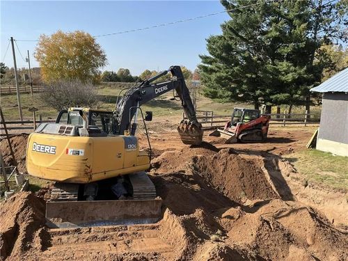 Man in a red hard hat looking into an open septic tank. Man in a red hard hat looking into an open septic tank.