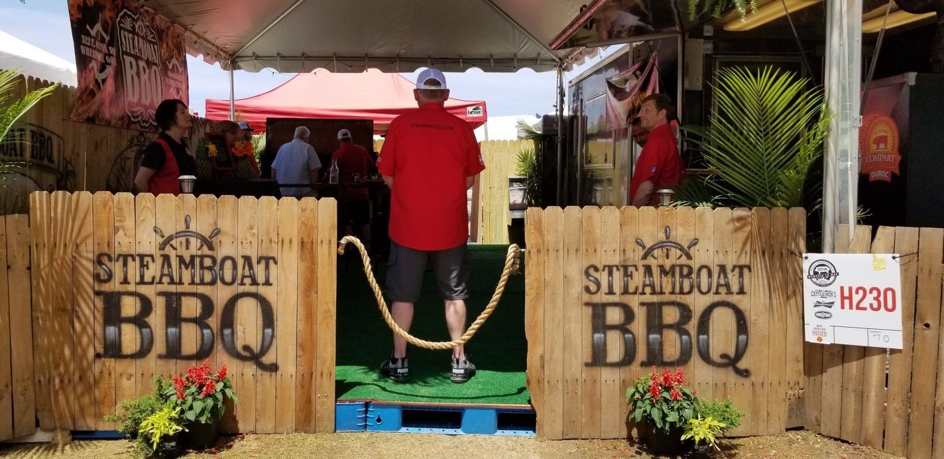 A man is walking between two wooden signs that say steamboat bbq
