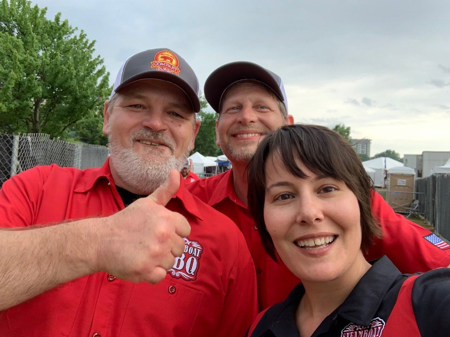 Three people are posing for a picture and one of them is giving a thumbs up.