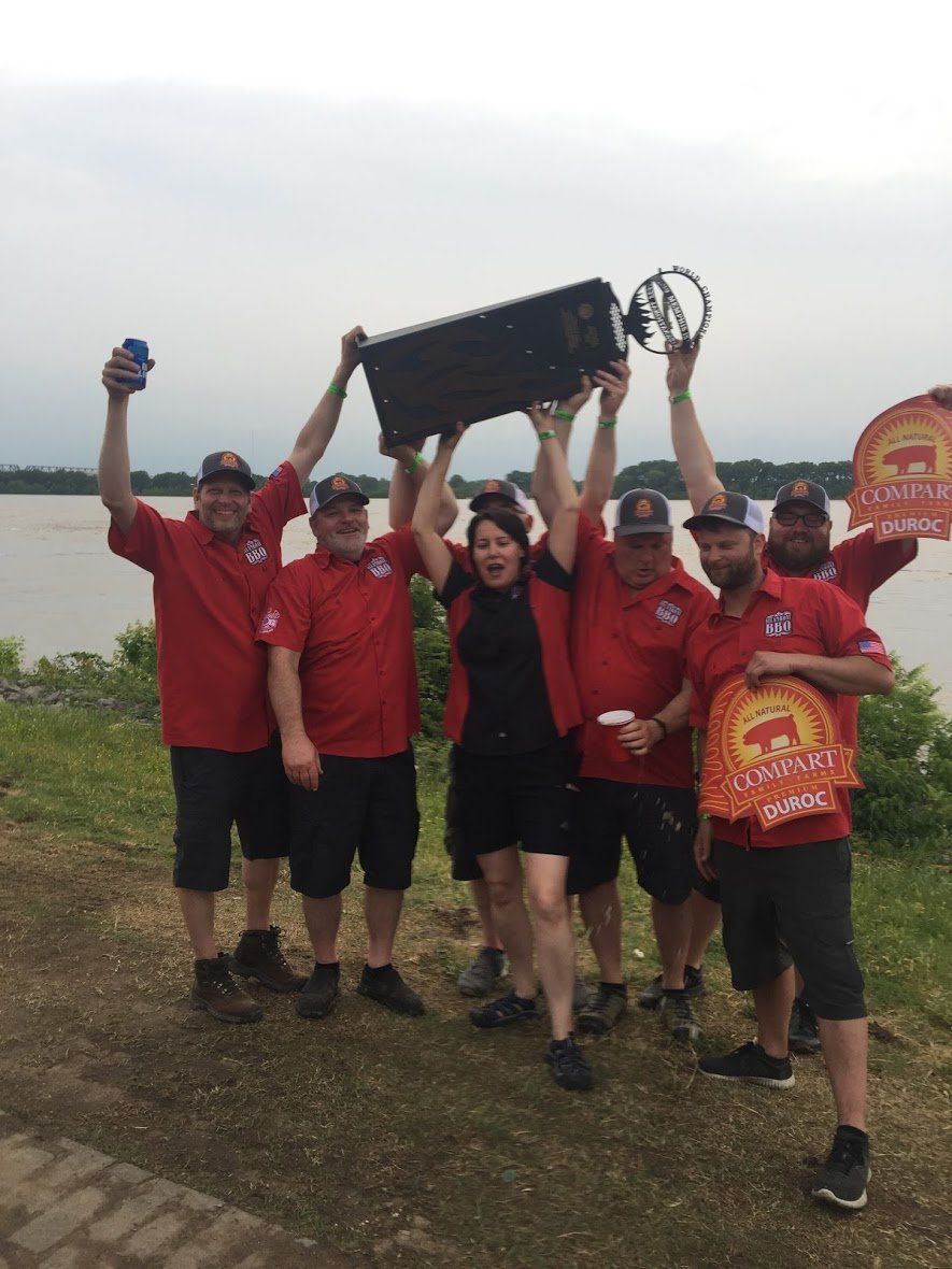 A group of people in red shirts are holding up a trophy