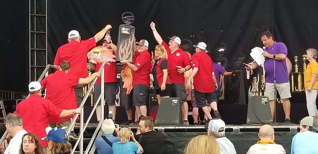 A group of people are standing on a stage holding a trophy.