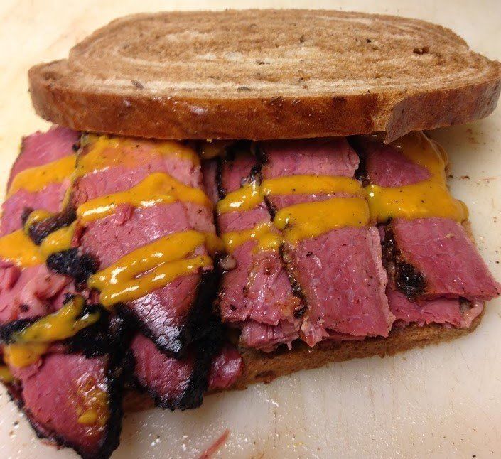 A sandwich with meat and mustard on a piece of bread