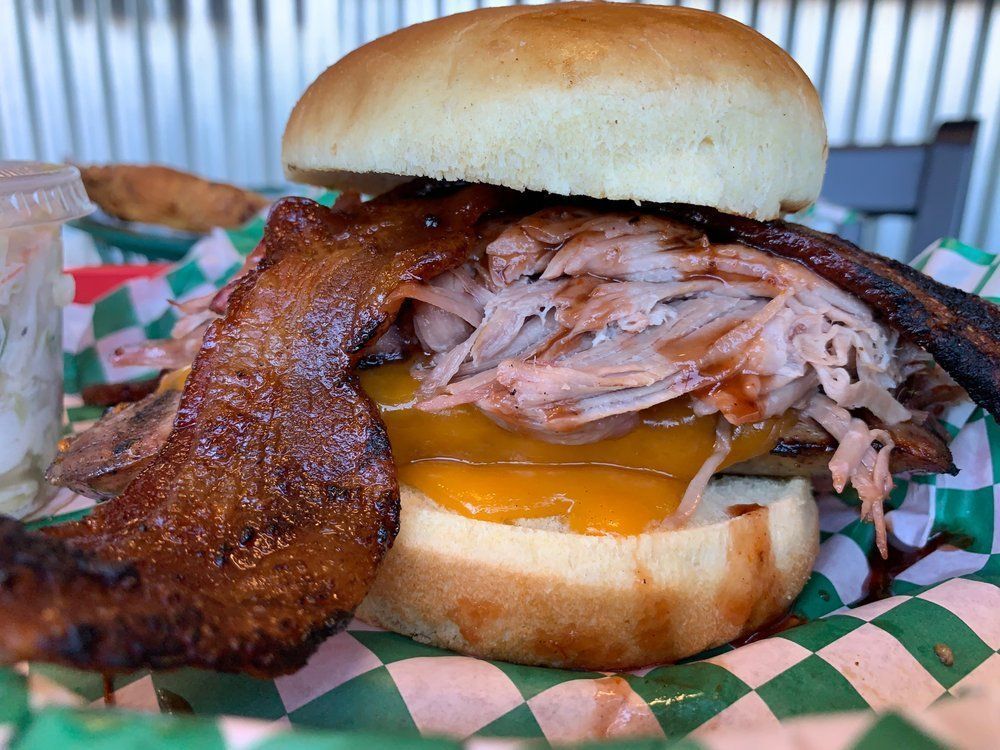 A pulled pork sandwich with bacon and cheese on a bun