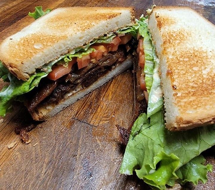 A sandwich is cut in half on a wooden cutting board