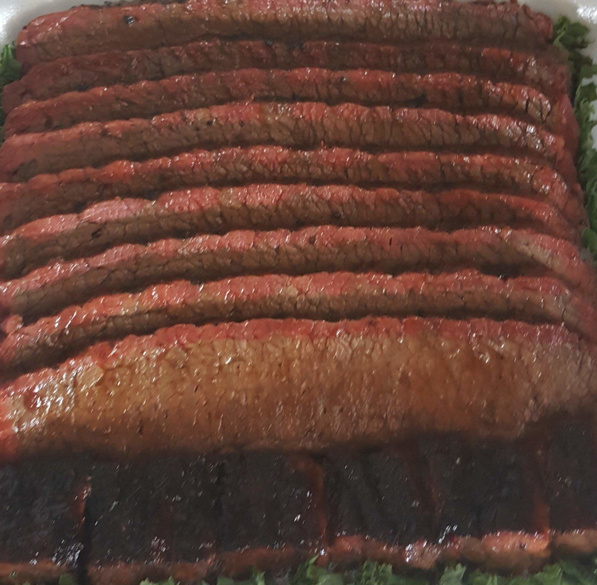A large piece of meat is sitting on top of lettuce in a styrofoam container