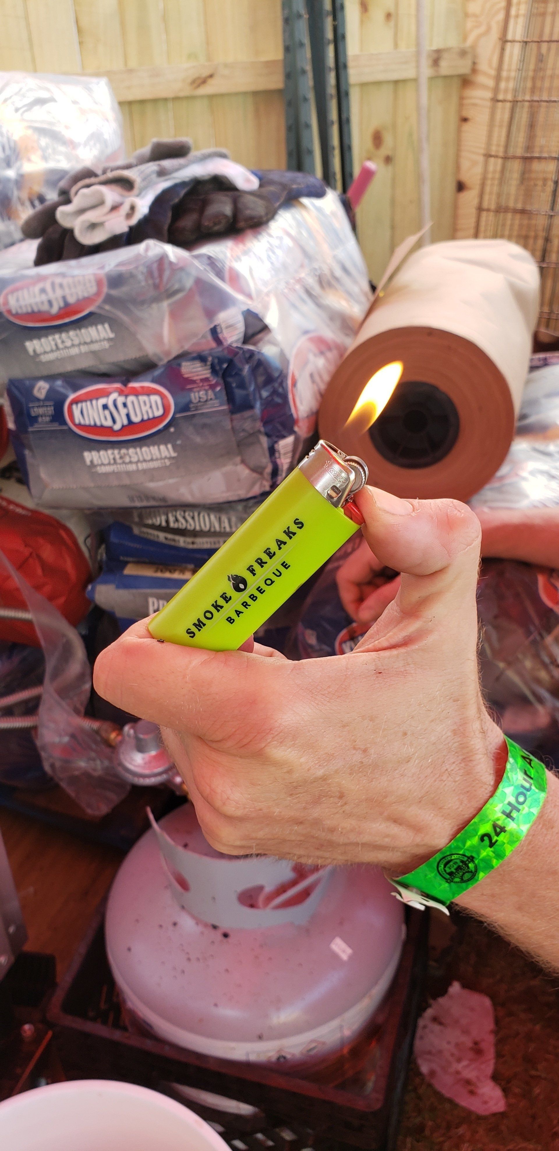 A person is holding a lighter in their hand in front of a pile of toilet paper.