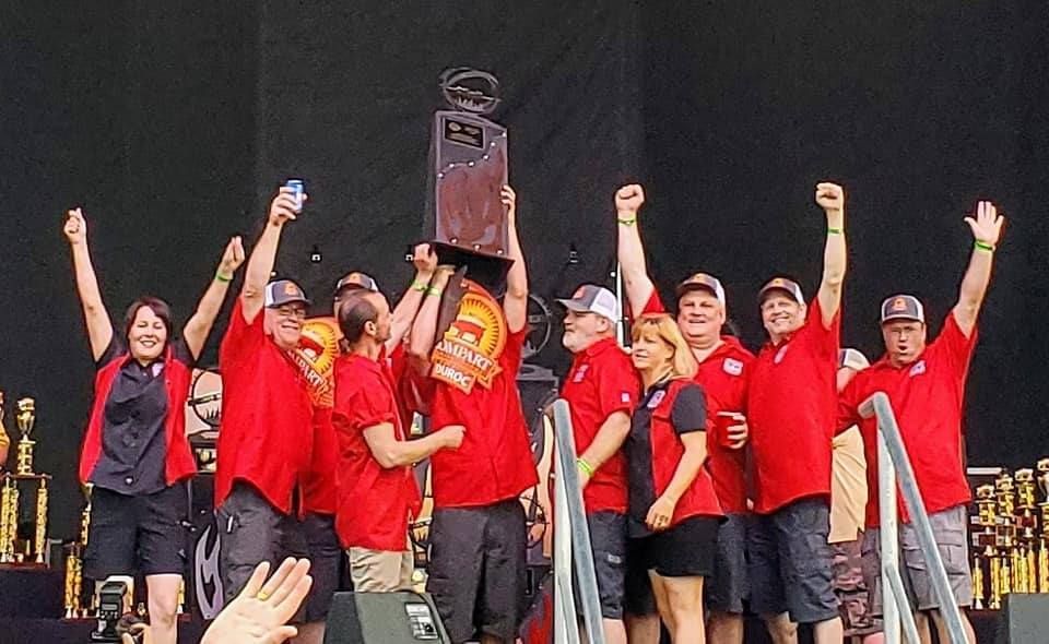 A group of people in red shirts are holding a trophy in their hands.