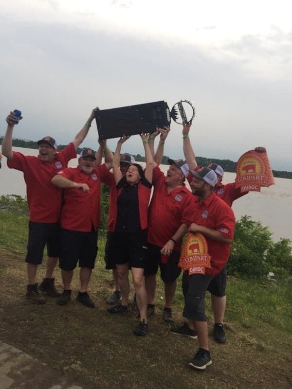 A group of people holding up a trophy in front of a body of water