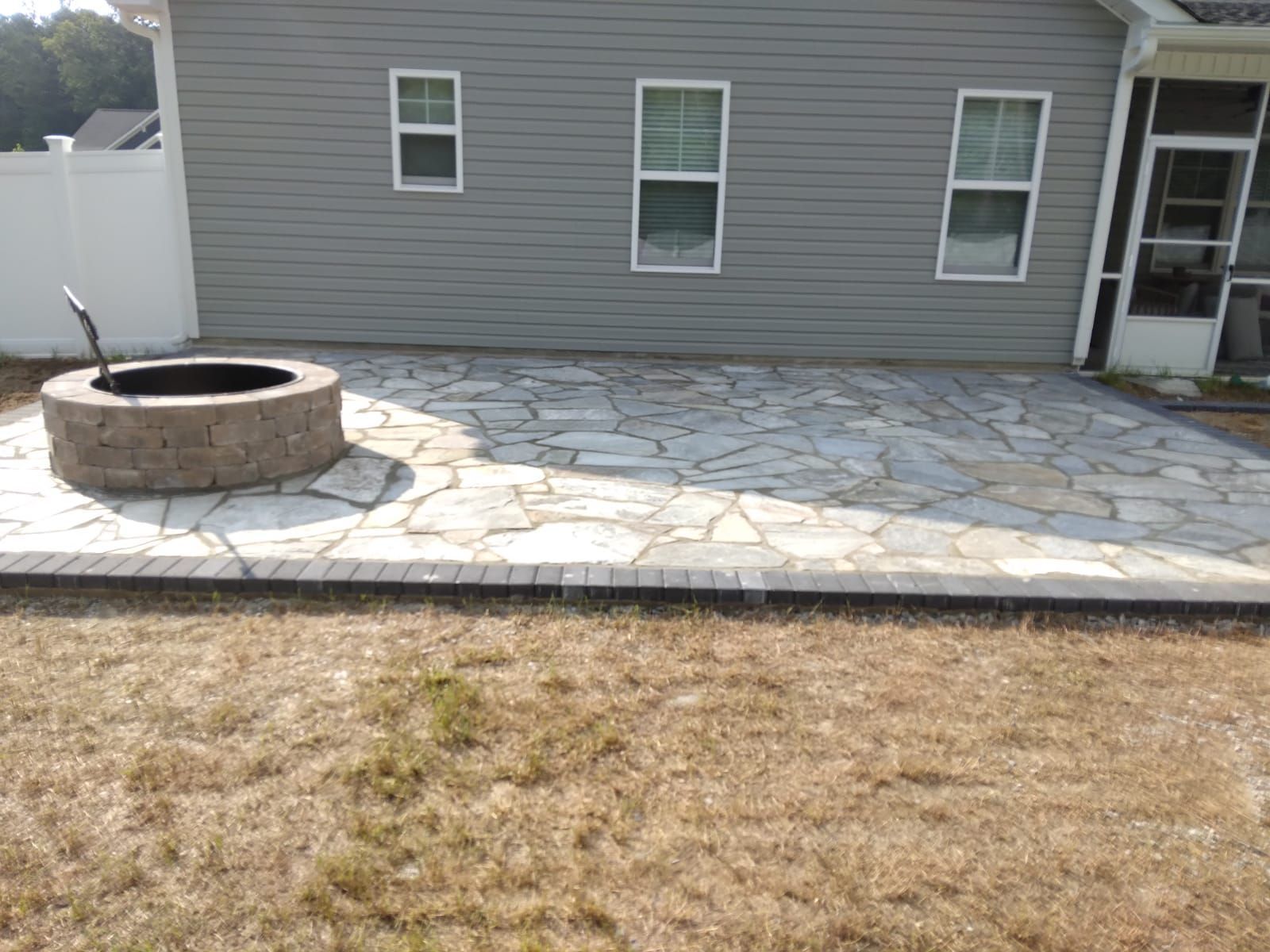 a fire pit sits on a stone patio in front of a house
