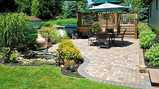 a patio with a table and chairs and an umbrella in a backyard .