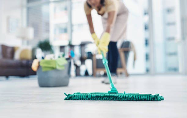 A woman mopping the floor to clean it
