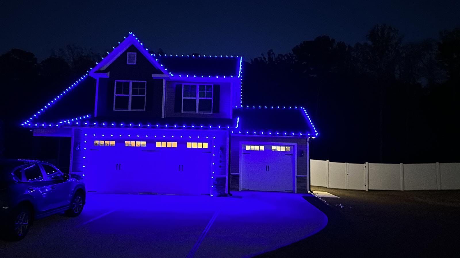 A house is lit up with blue lights and a car is parked in front of it.