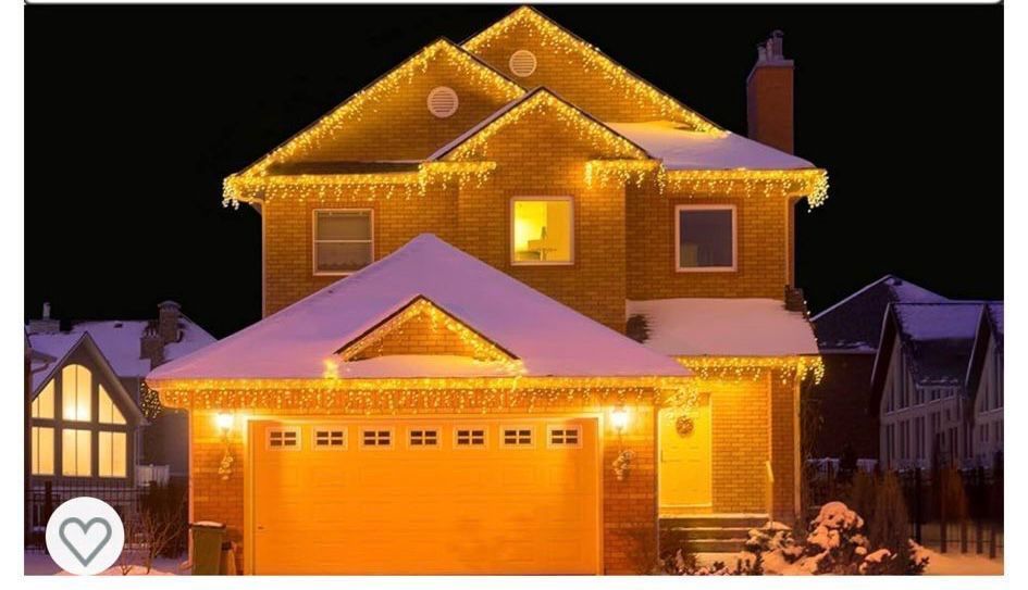 A house is decorated with christmas lights and snow on the roof.