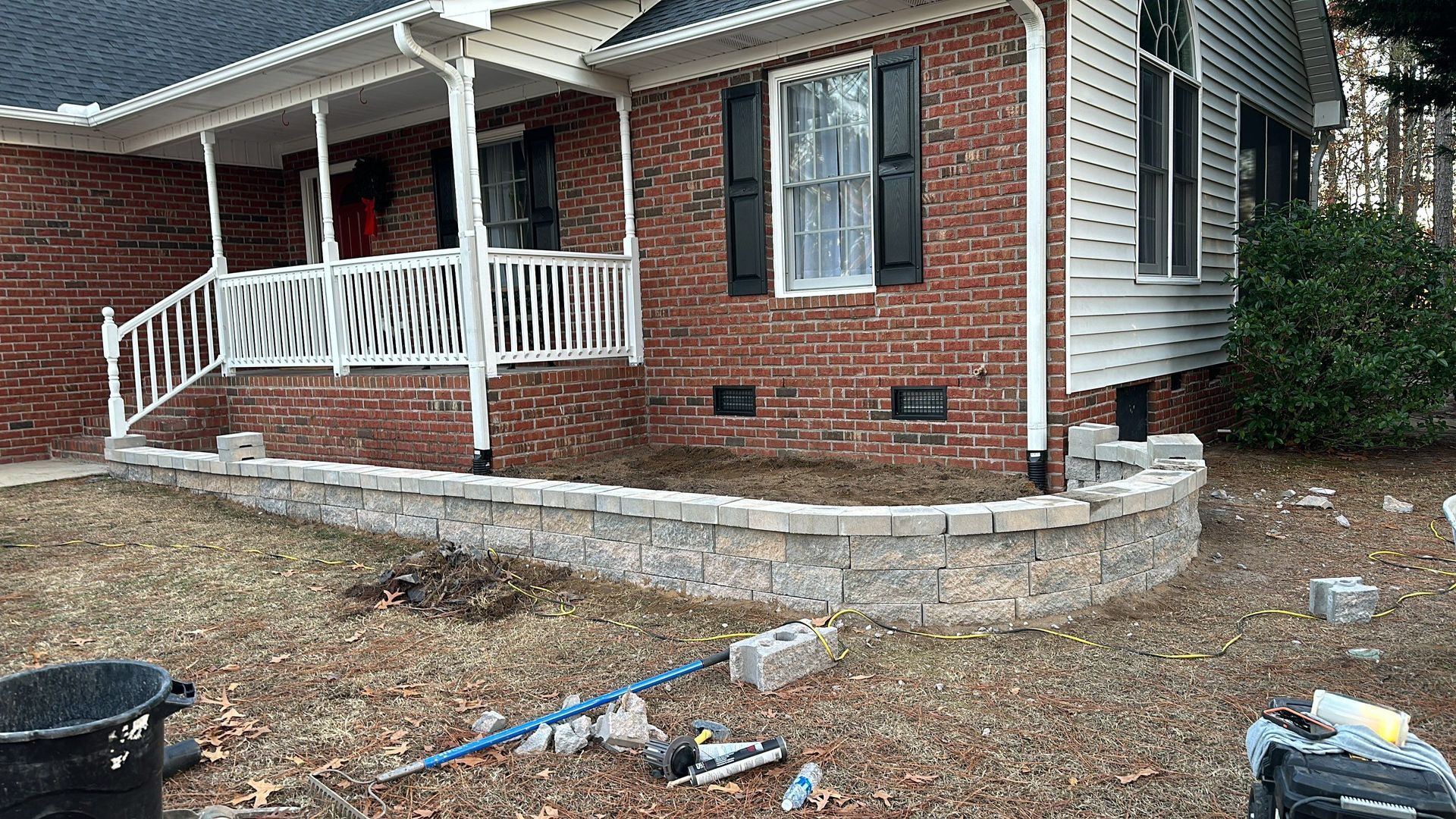 a brick house with a porch and a stone wall in front of it .