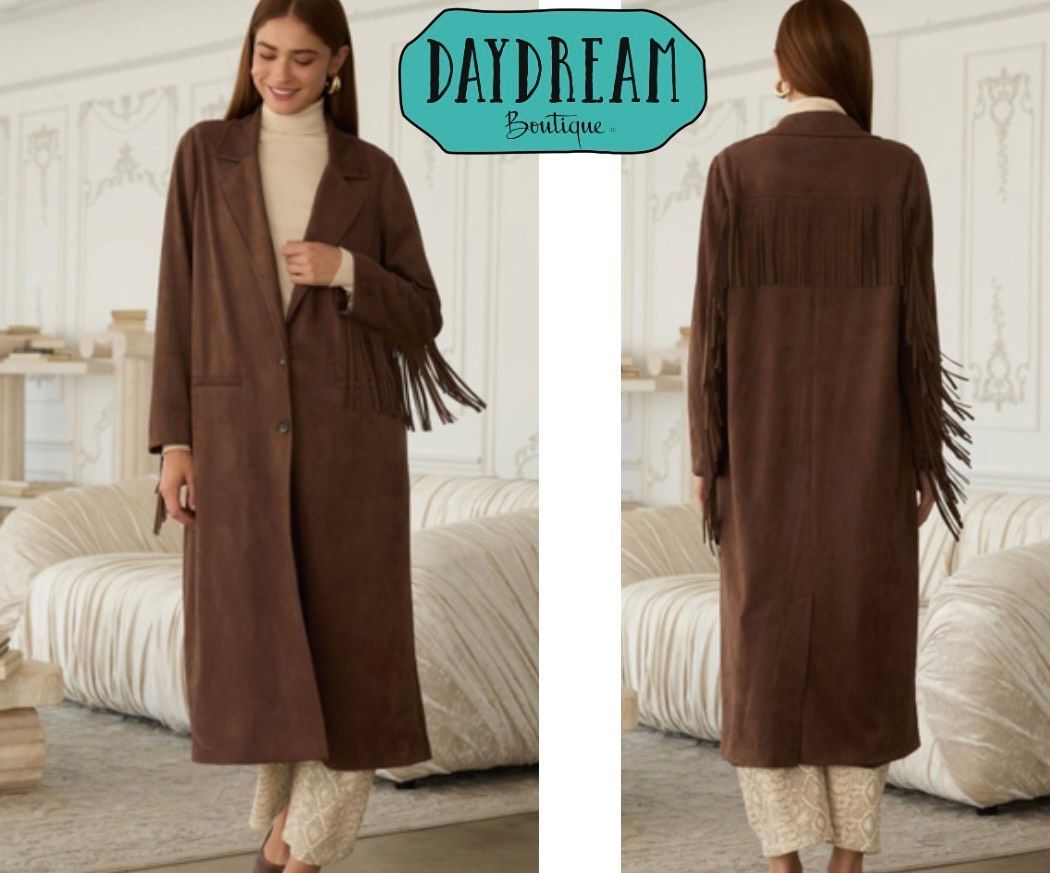 Woman in brown coat with fringe, standing in a room.