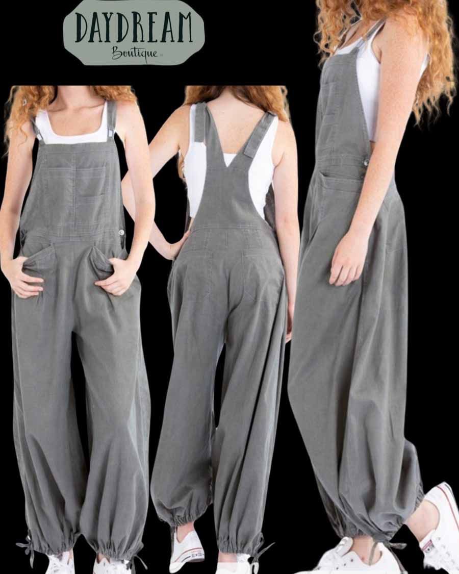 Woman wearing gray overalls with white tank top and sneakers.