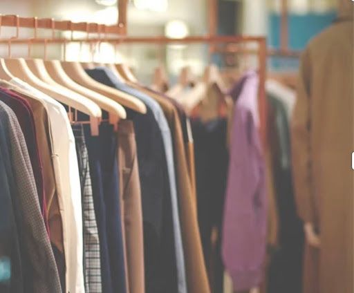 Clothes hanging on a rack inside a store, various colors visible.