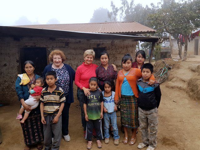 Eine Gruppe von Menschen steht vor einem kleinen Haus.