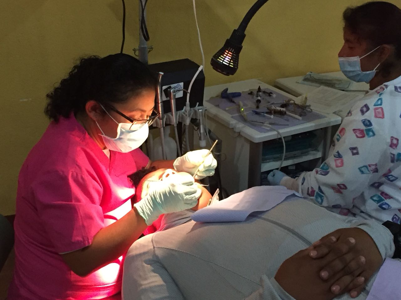 Ein Zahnarzt untersucht die Zähne eines Patienten, unterstützt von einer zahnärztlichen Assistentin in einer Klinik.