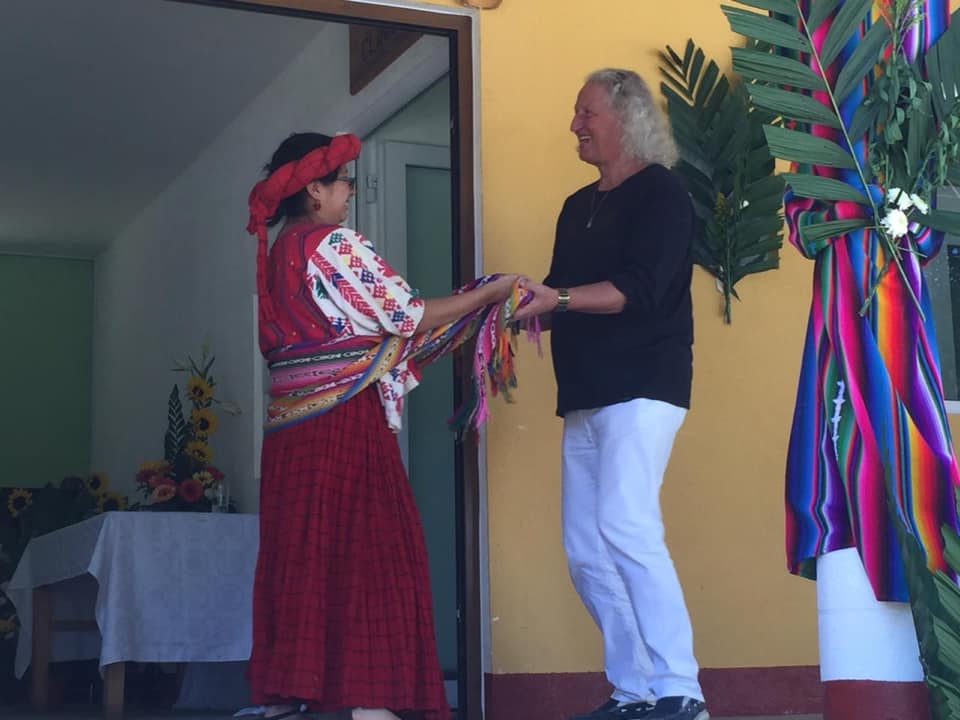 Eine Frau in einem roten Kleid und ein Mann, der bunte Bänder hält, tanzen möglicherweise im Freien.