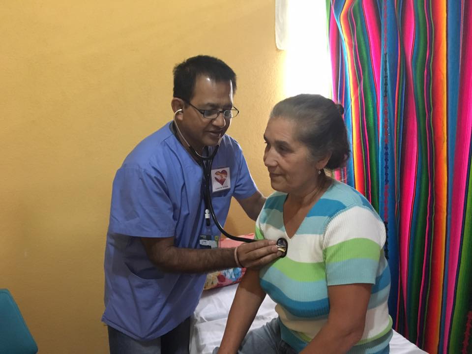 Ein Arzt hört in einem hell erleuchteten Raum mit einem Stethoskop die Brust des Patienten ab.