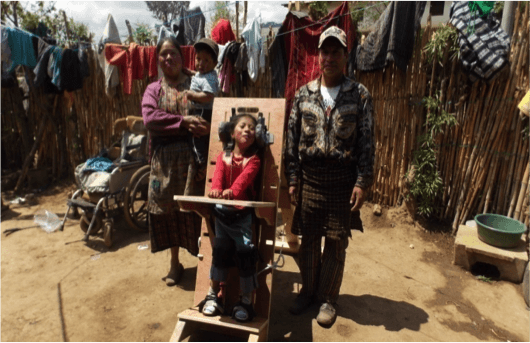 Eine Familie steht draußen, ein Kind befindet sich in einem eigens angefertigten Stehgestell.