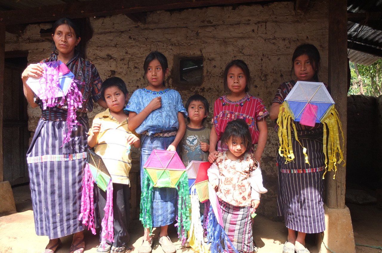 Gruppe von Kindern in traditioneller Kleidung, die bunte Drachen halten.