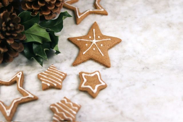 Gingerbread cookies in the shape of stars are sitting on a table next to a pine cone.