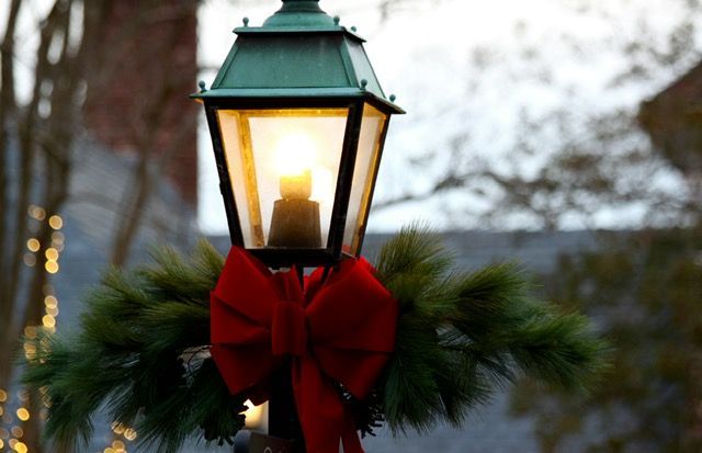 A street light decorated for christmas with a red bow