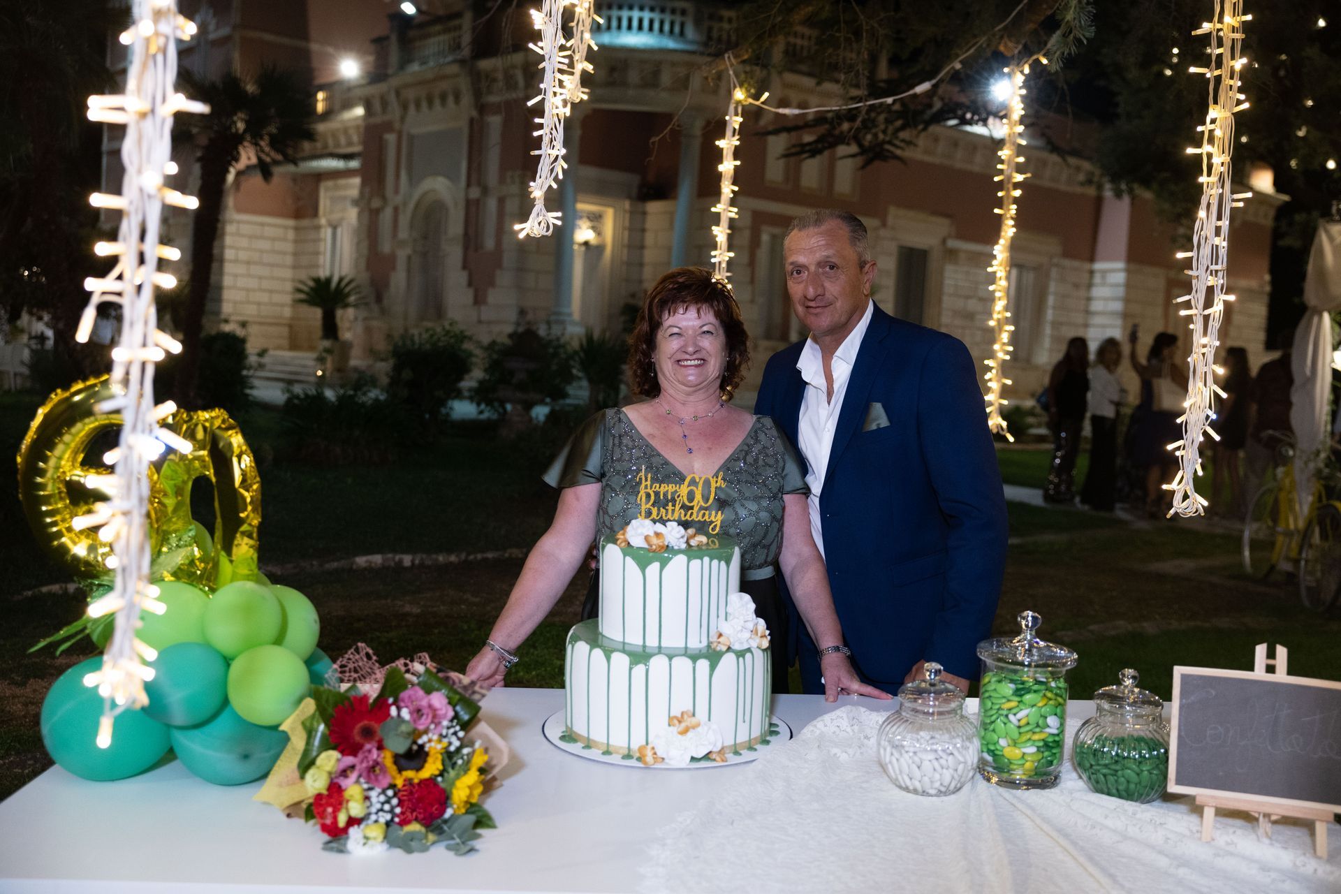 Coppia in posa accanto a una torta a due piani con la scritta 