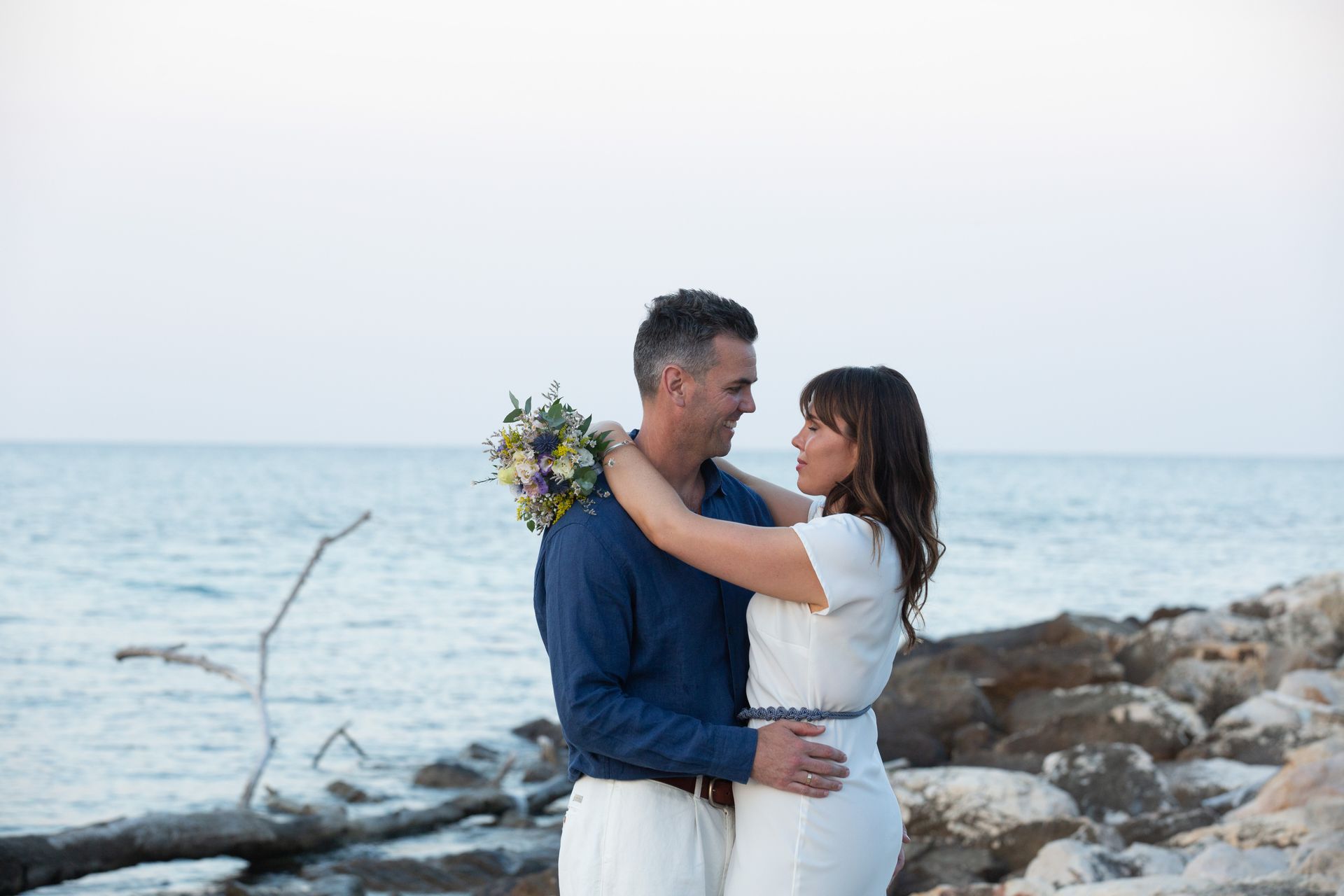 abbraccio romantico degli sposi davanti al mare al tramonto
