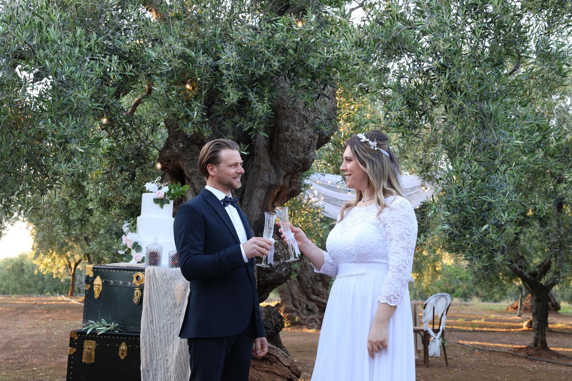 brindisi degli sposi davanti alla torta circondati da ulivi