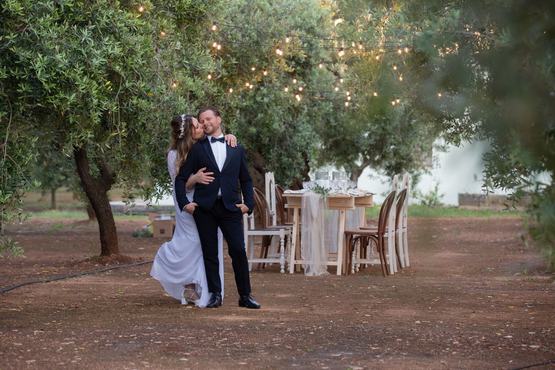 Coppia tra gli ulivi davanti a un tavolo imperiale con atmosfera di luci 