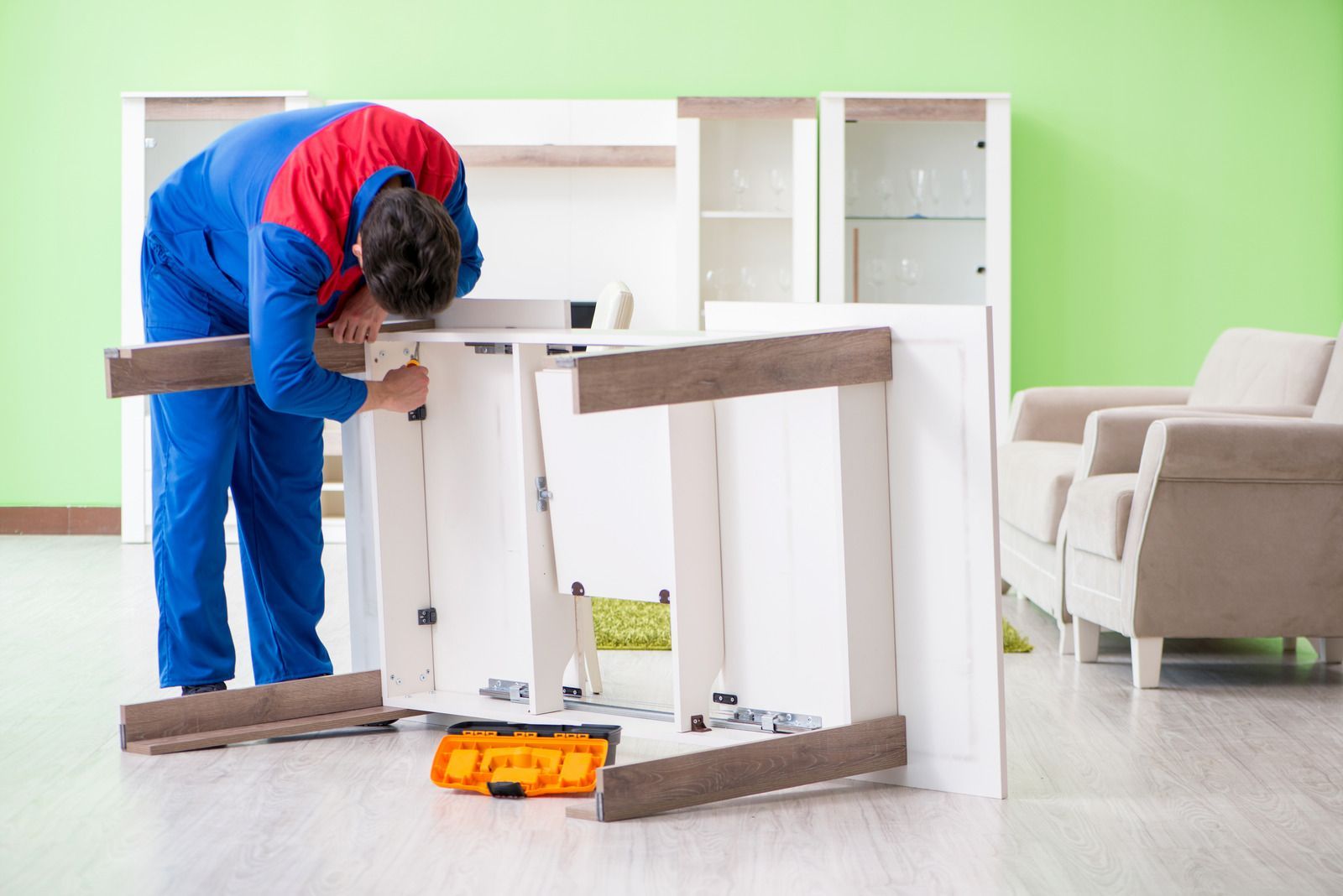 A man is working on a piece of furniture in a living room.