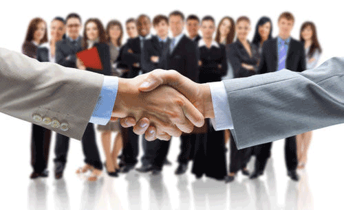 Two men are shaking hands in front of a group of people.