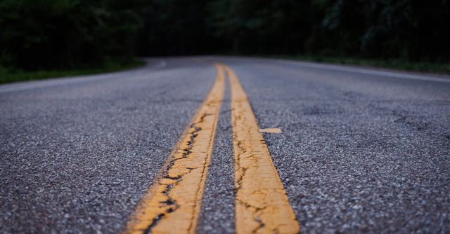 A close up of a road with two yellow lines on it.