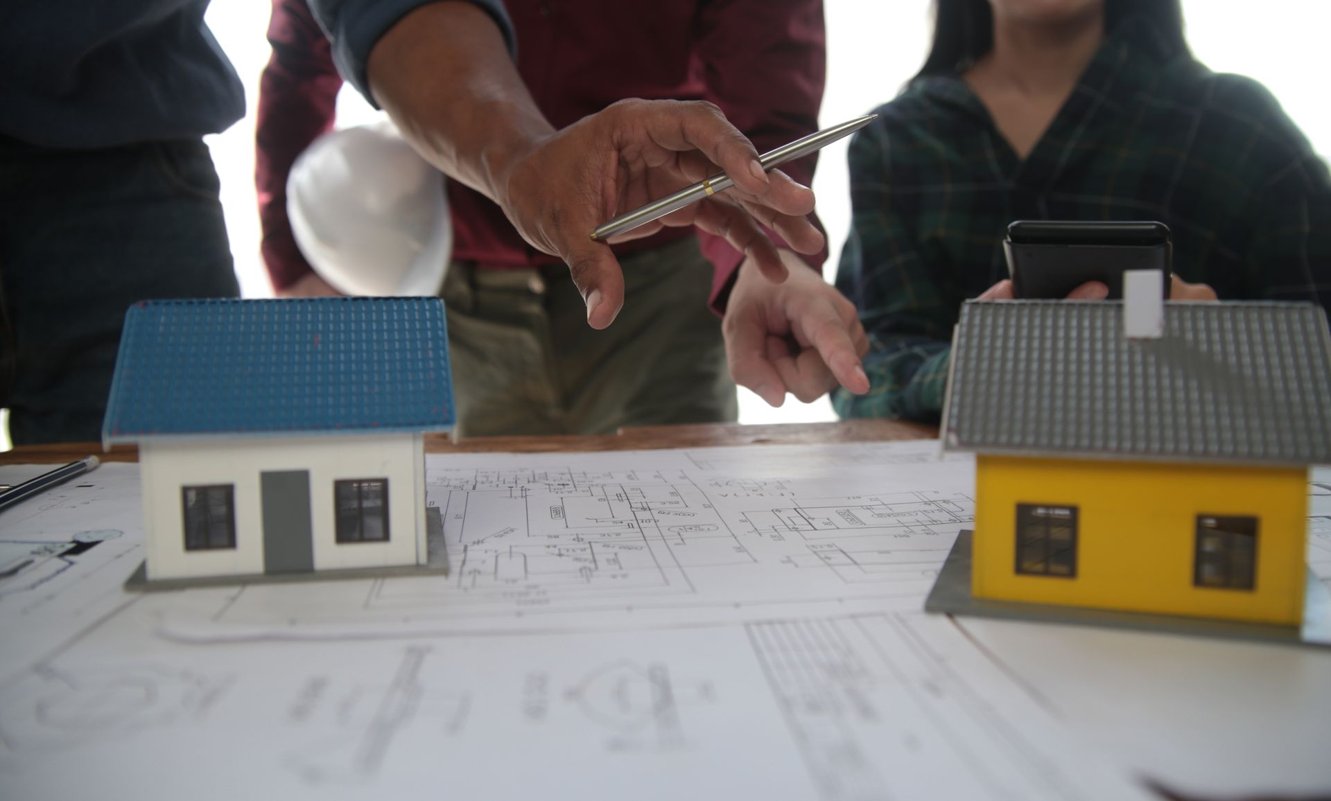 A group of people are sitting at a table with model houses and blueprints.